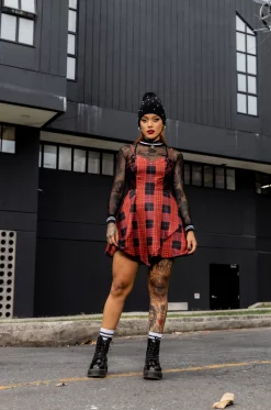 Vestido tipo overol en rolex sublimado con estampado de cuadros exclusivo de nuestra marca, escote en V, tiras graduables, cortes delanteros laterales en blonda rígida, bolsillos laterales, asimetría en largo delantero y cierre posterior. / Overall-style dress in sublimated rolex fabric with an exclusive checkered print from our brand, V-neckline, adjustable straps, side front cuts in rigid lace, side pockets, asymmetrical front length, and back closure.