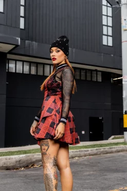 Vestido tipo overol en rolex sublimado con estampado de cuadros exclusivo de nuestra marca, escote en V, tiras graduables, cortes delanteros laterales en blonda rígida, bolsillos laterales, asimetría en largo delantero y cierre posterior. / Overall-style dress in sublimated rolex fabric with an exclusive checkered print from our brand, V-neckline, adjustable straps, side front cuts in rigid lace, side pockets, asymmetrical front length, and back closure.