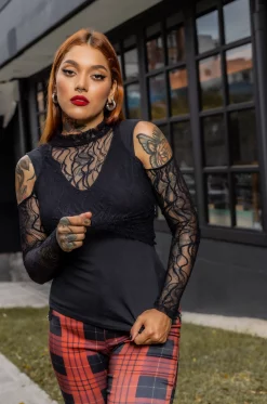 Camisa con croptop en blonda grabada y cuello alto, aberturas en hombros y manga larga y camisa tipo esqueleto en algodón lycrado negro./ Shirt with a croptop in engraved lace and high neck, shoulder and long sleeve openings, and skeleton-style shirt in black lycra cotton.