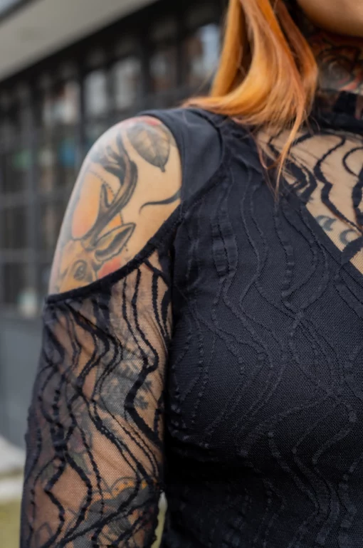 Camisa con croptop en blonda grabada y cuello alto, aberturas en hombros y manga larga y camisa tipo esqueleto en algodón lycrado negro./ Shirt with a croptop in engraved lace and high neck, shoulder and long sleeve openings, and skeleton-style shirt in black lycra cotton.