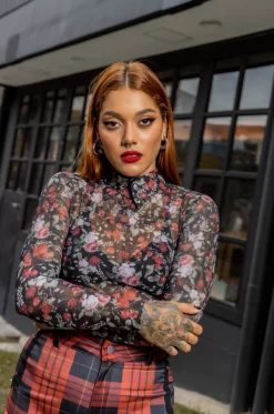 Croptop en Mallatex sublimada con diseño de estampado de flores exclusivos de nuestra marca, con cuello en Rolex sublimado, mangas largas y cierre posterior con broche. Tejido de punto. / Cropped top in sublimated Mallatex fabric featuring our brand's exclusive floral print design. It showcases a sublimated Rolex neckline, long sleeves, and a back closure with a clasp. Crafted in a knit fabric