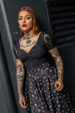 Camisa tipo croptop en Rolex negro, con silueta ajustada, escote tipo corazón, varillas, mangas en blonda rígida y cierre posterior tipo corset. / Black croptop shirt in black Rolex fabric, with a fitted silhouette, sweetheart neckline, boning, rigid lace sleeves, and a corset-style back closure. Puedes combinar esta prenda con la falda Under the bridge.